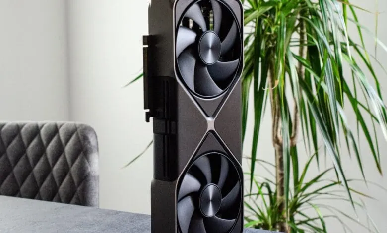 Nvidia RTX 5080 graphics card stands upright on a table, showcasing its dual fans and sleek design.