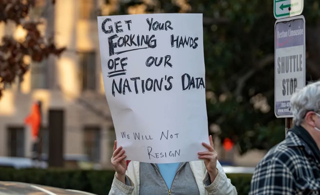fork-data-breach-musk-doge. Protester holding Sign taht reads: Get your Forking Hands Off Our Nations DATA
