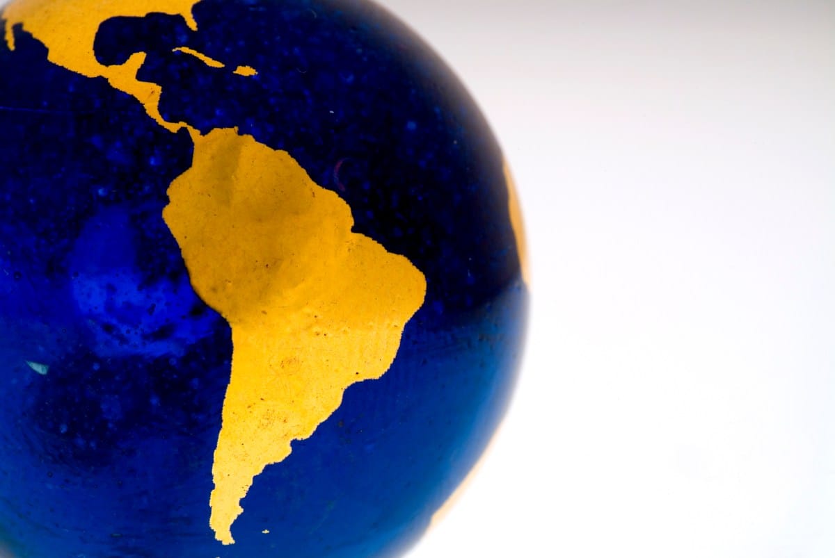 Close-up of a small glass globe; South America is highlighted in gold on a deep blue background.