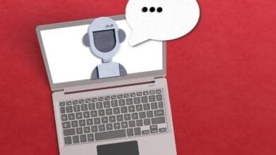 Laptop screen displays a paper robot with a speech bubble, suggesting AI customer service or chatbot interaction.