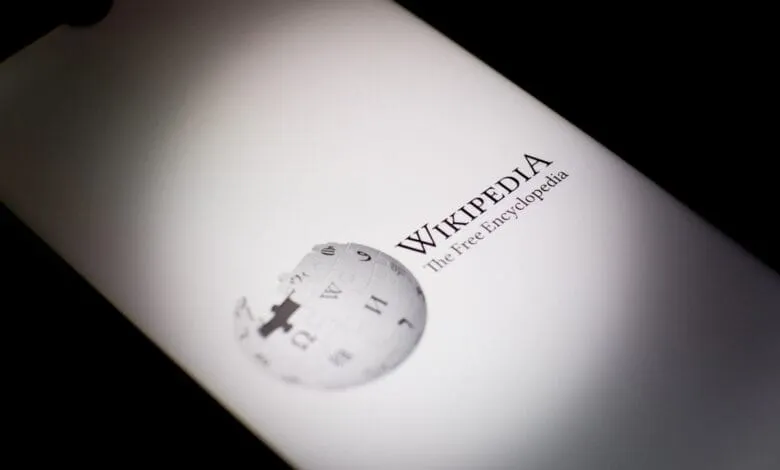 Close-up of a smartphone displaying the Wikipedia logo and tagline: 'The Free Encyclopedia'.