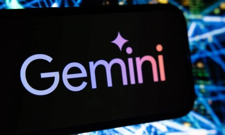 Close-up of a smartphone displaying the Gemini cryptocurrency exchange logo. Blurred network cables in the background.