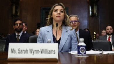 Sarah Wynn-Williams testifies at a hearing, wearing a light blue blazer. Others sit in the background.