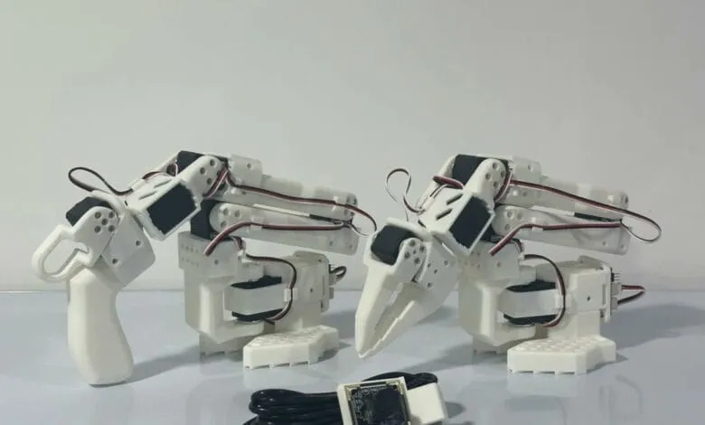 Two white robotic arms with claw-like grippers and a small camera module.