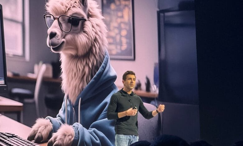 A man presents at a tech conference, a large screen behind him shows an illustration of a llama wearing glasses and a hoodie using a computer.