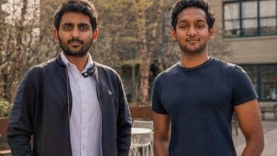 Two young men, co-founders of Nuvo, stand outdoors. One wears a dark jacket over a light shirt; the other wears a dark t-shirt.