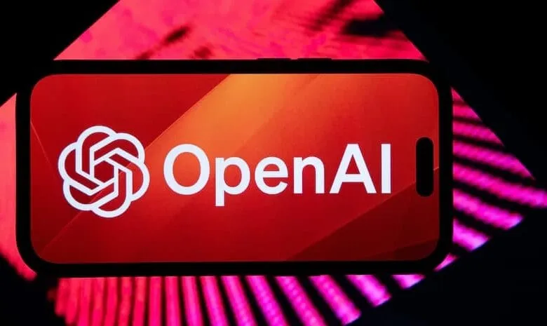 Close-up of a smartphone displaying the OpenAI logo: a white stylized flower and the text 'OpenAI' on a red background.