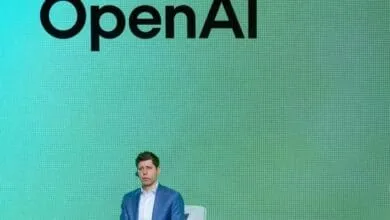 OpenAI CEO Sam Altman sitting on chair on a stage, green background
