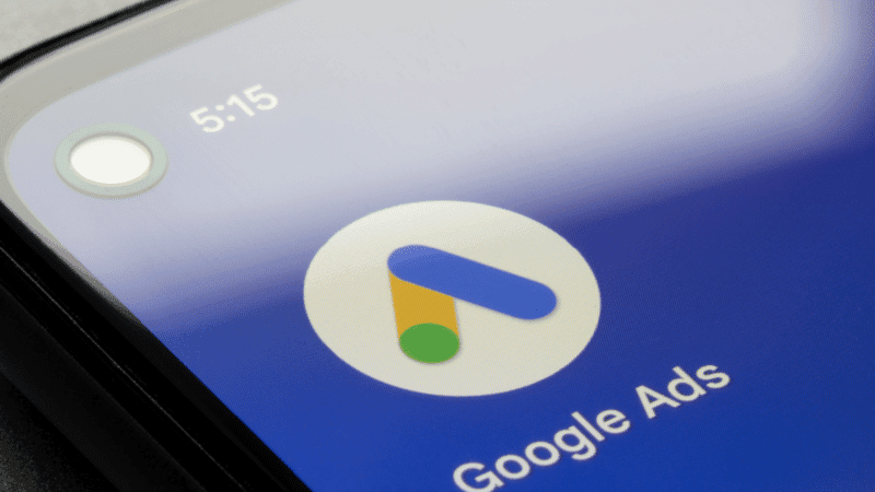 Close-up of a smartphone displaying the Google Ads app icon and text on a blue background.