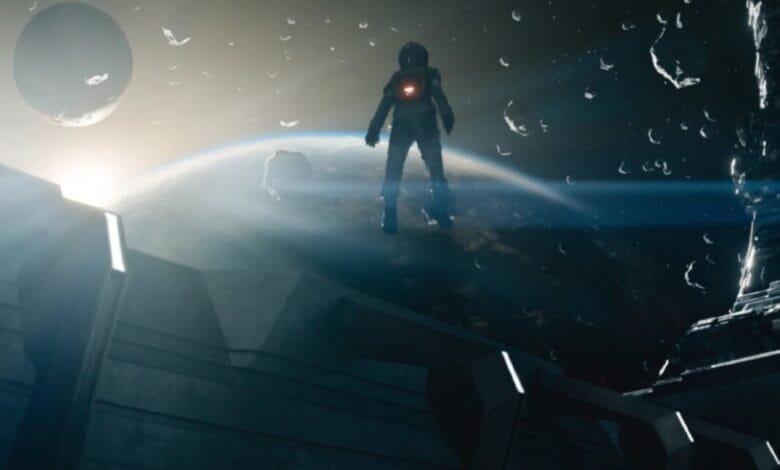 A lone astronaut stands on a space station overlooking Earth and a distant moon, debris floating in space around them.