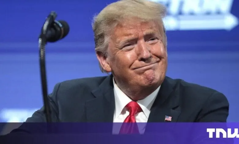 Close-up of Donald Trump, former US President, wearing a dark suit and red tie, at a podium.