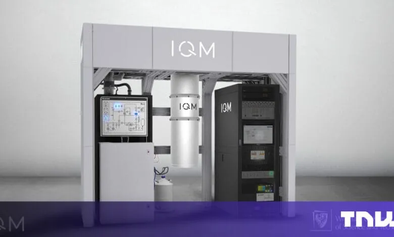 A sleek, gray quantum computer, the IQM, stands in a modern room. Control panels and server racks are visible.