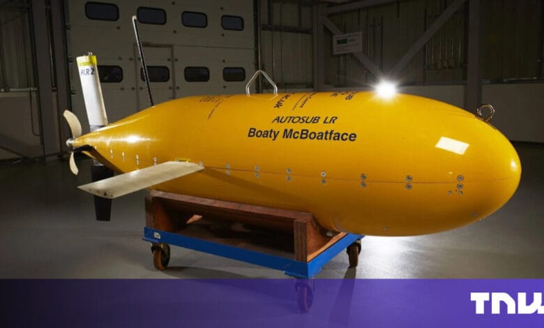 Yellow autonomous underwater vehicle, 'Boaty McBoatface', on a wheeled platform in a hangar.