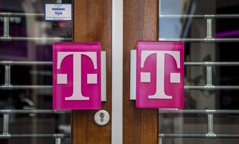 Two magenta T-Mobile logos on a wood door behind a security gate. The store appears closed.