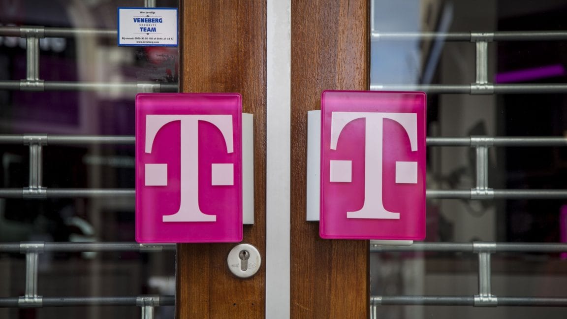 Two magenta T-Mobile logos on a wood door behind a security gate. The store appears closed.