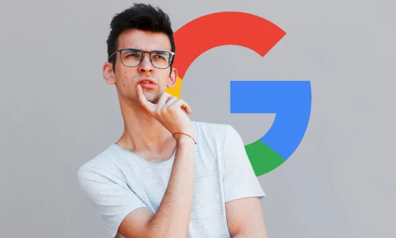 A young man wearing glasses thoughtfully touches his chin, with a large Google logo behind him.
