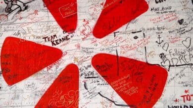 A world map covered in red handprints and various handwritten messages, signatures, and drawings.