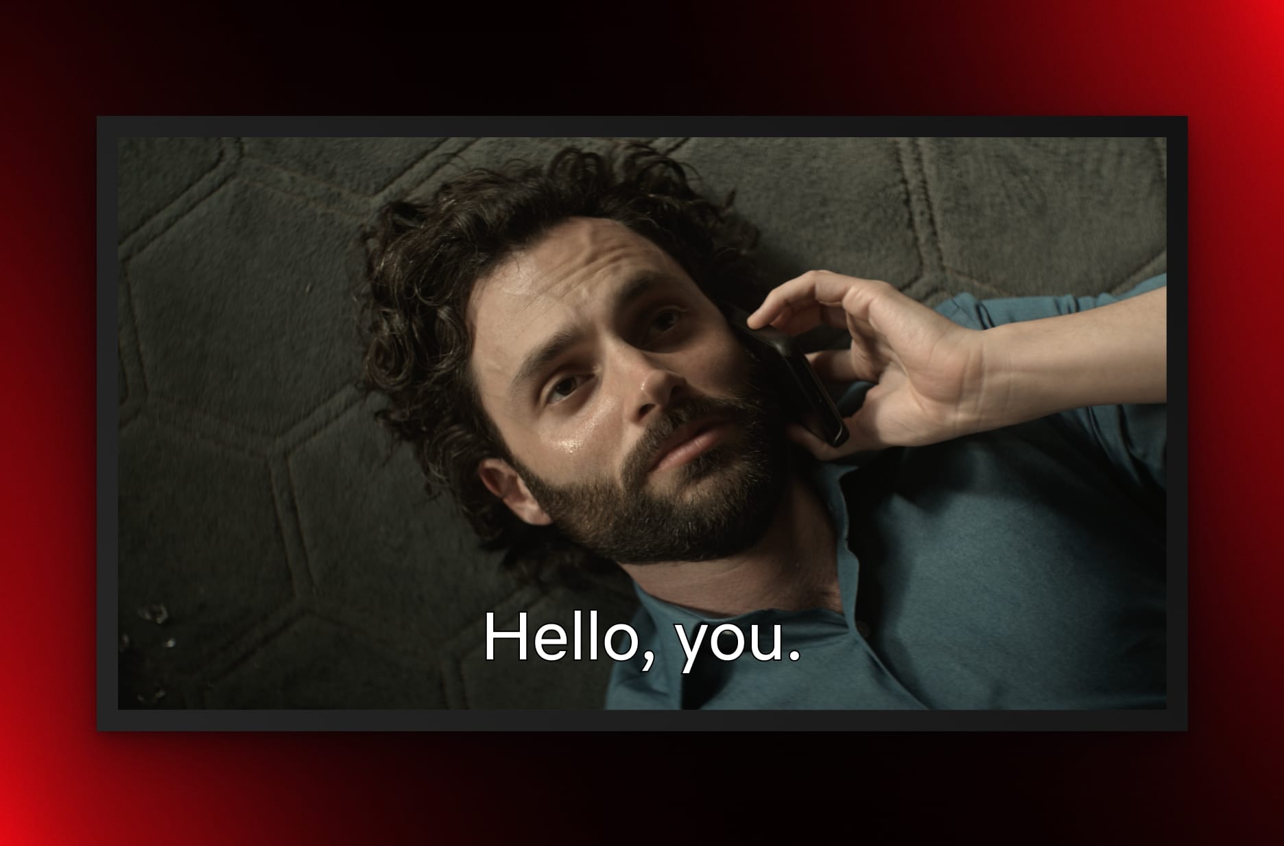Penn Badgley, as Joe Goldberg in You, lies on the floor, looking up at the camera while on a phone call. The words 'Hello, you.' are superimposed.