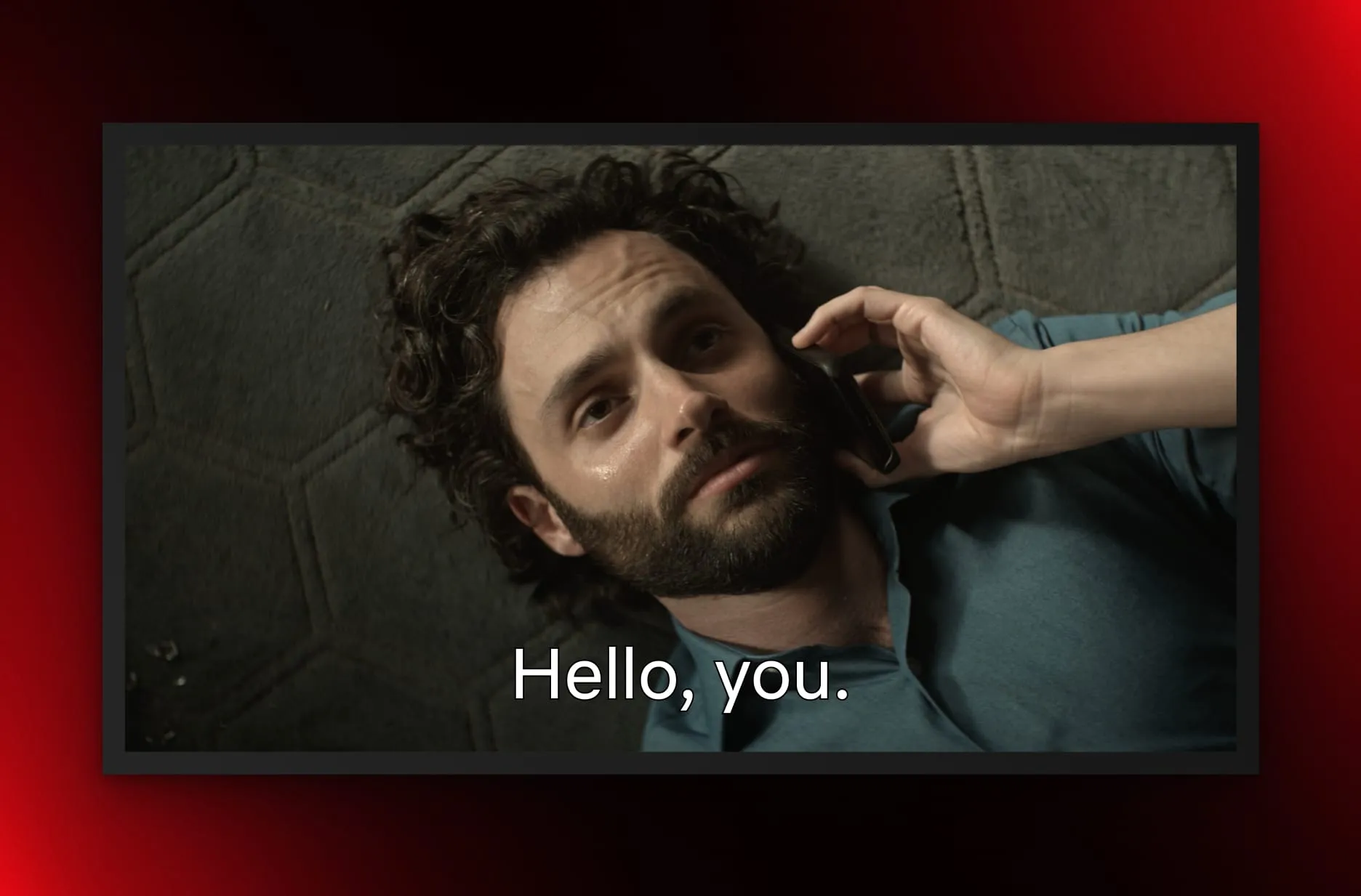 Penn Badgley, as Joe Goldberg in You, lies on the floor, looking up at the camera while on a phone call. The words 'Hello, you.' are superimposed.