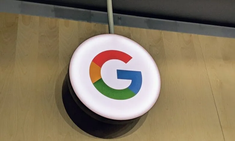 Backlit Google logo in its signature colors on a light wood wall.