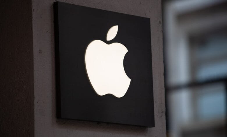 Illuminated Apple logo on a dark square sign, mounted on a wall.