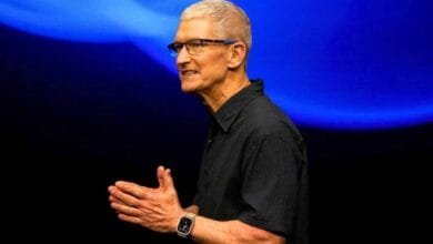 Tim Cook, Apple CEO, speaks at a presentation against a vibrant blue backdrop.