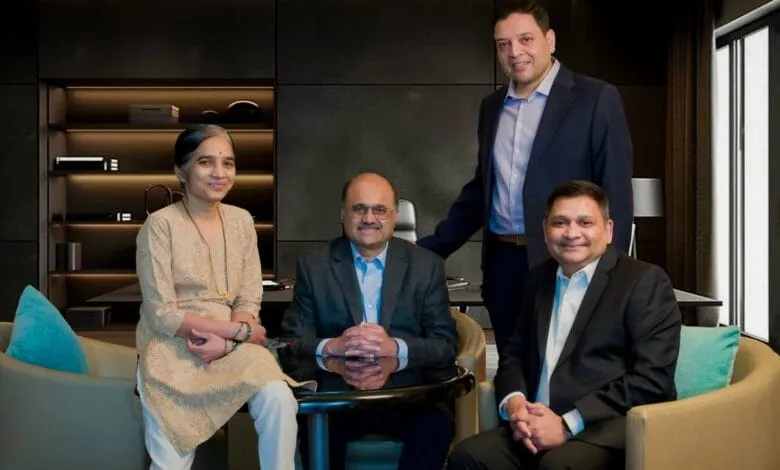 Four business leaders pose for a professional portrait in a modern office setting.