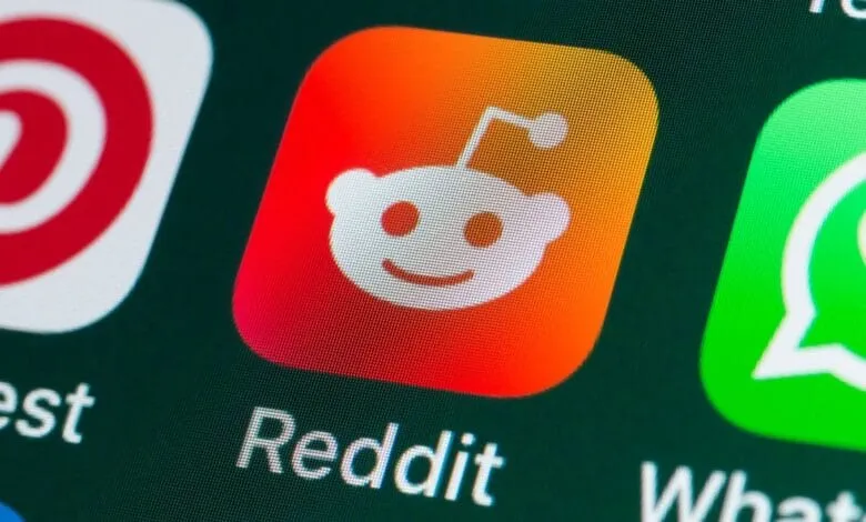 Close-up of the Reddit app icon on a smartphone screen, featuring the white alien mascot on an orange-red gradient.