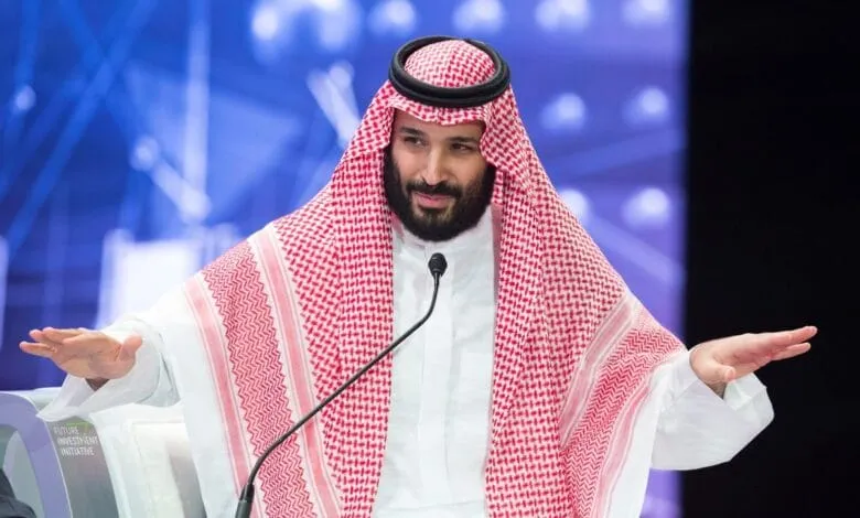 Crown Prince Mohammed bin Salman speaks at a conference, wearing traditional Saudi Arabian attire.