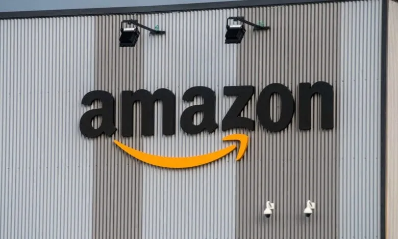 Large Amazon logo on a corrugated metal building, with security lights and cameras.