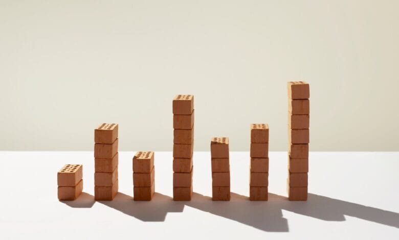 Six stacks of small terracotta bricks of varying heights, arranged like a bar graph against a light beige background.