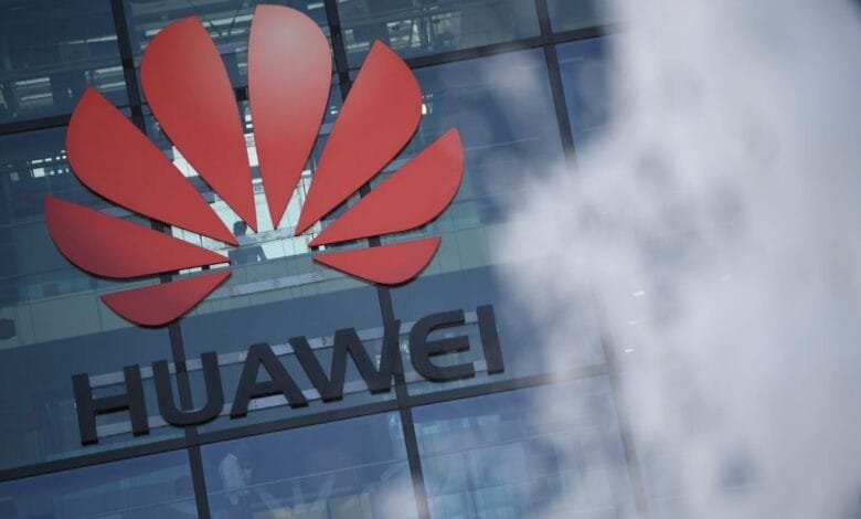 Huawei logo, a stylized red flower, on a modern glass building.