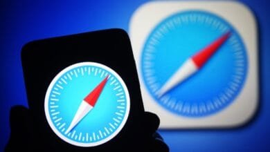 Close-up of a smartphone displaying the Safari browser icon: a compass on a blue background. A blurred background shows the same icon.
