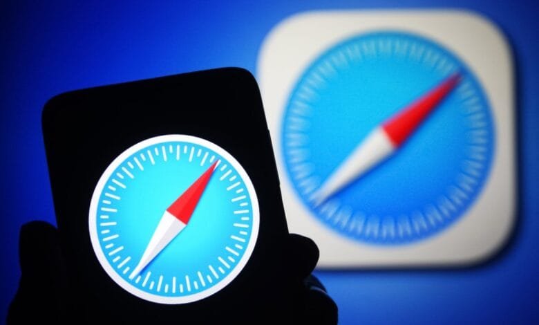 Close-up of a smartphone displaying the Safari browser icon: a compass on a blue background. A blurred background shows the same icon.