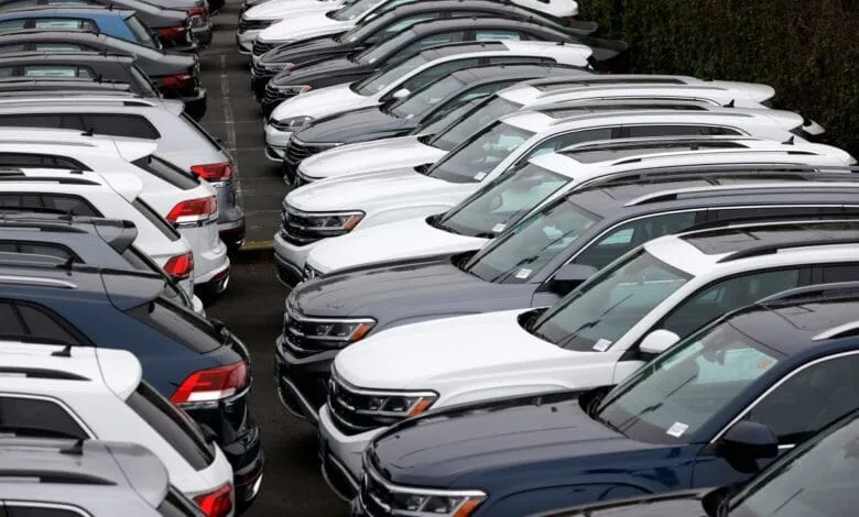 Rows of new white and dark-colored SUVs parked in a lot, suggesting a dealership or car inventory.