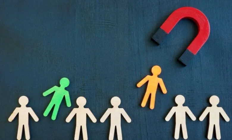 A red horseshoe magnet pulls an orange figure from a group of beige and green figures on a dark blue background.