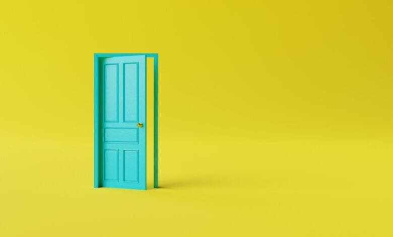 A teal door slightly ajar against a bright yellow background. The scene is minimalist and suggests new beginnings or opportunity.