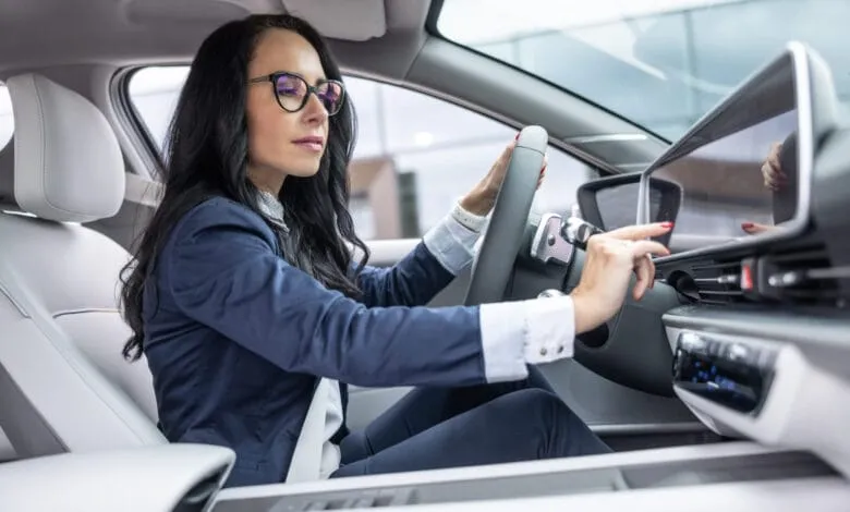 Businesswoman in glasses uses the infotainment screen in her electric car.