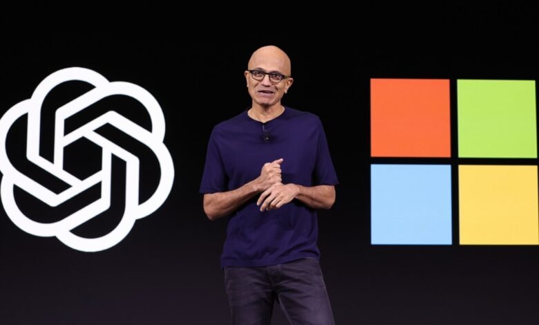 Satya Nadella, Microsoft CEO, speaks on stage at a Microsoft event. The Microsoft logo is visible behind him.