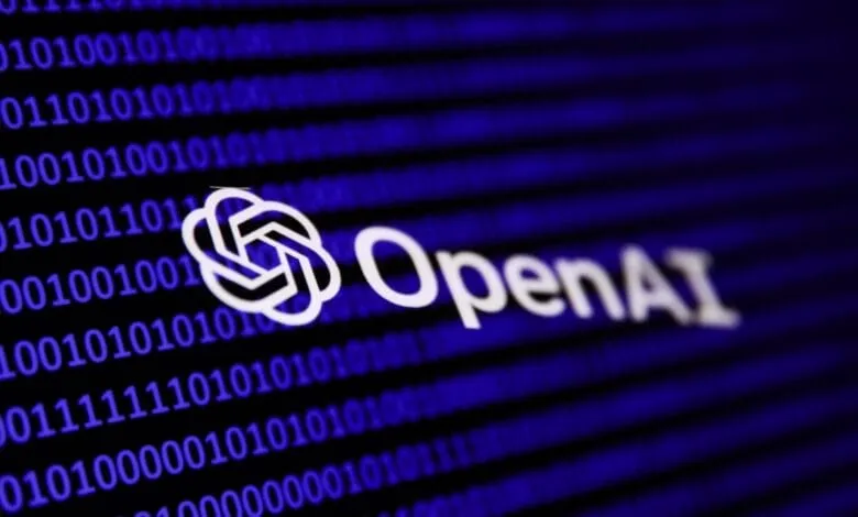 Close-up of the OpenAI logo in white, set against a blurred background of blue binary code.