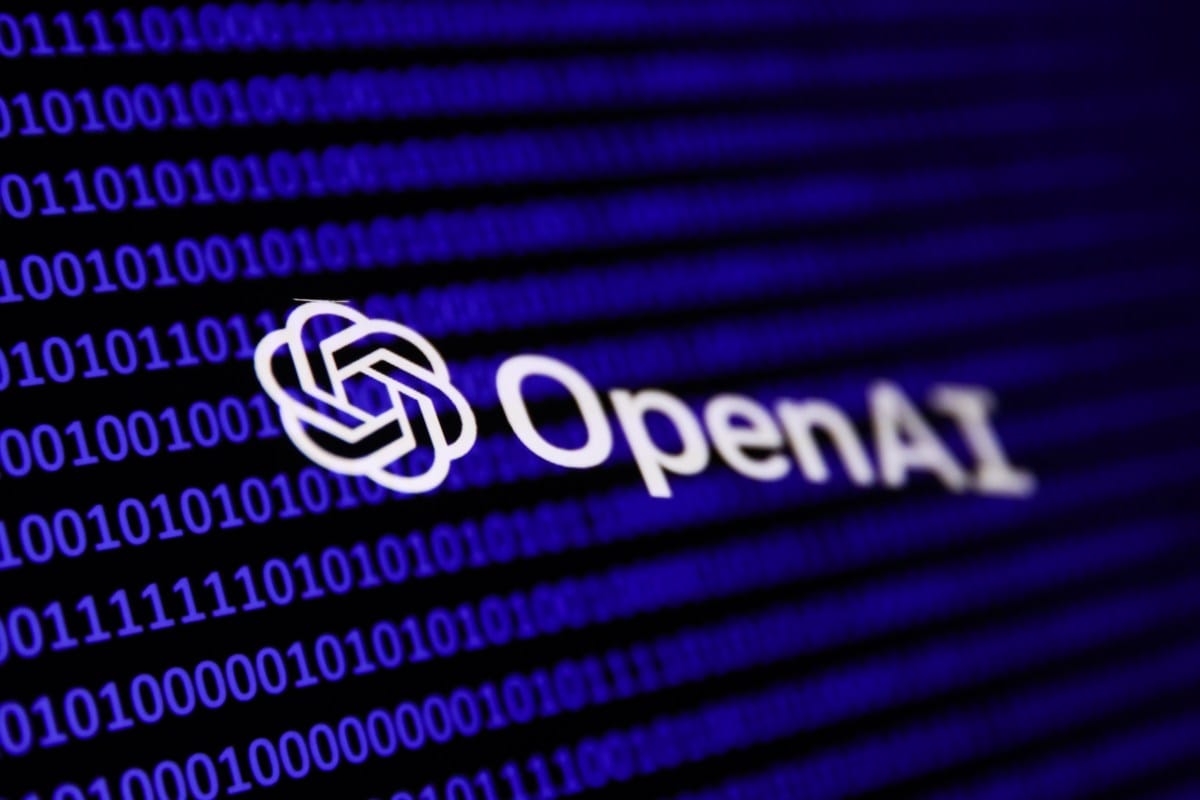 Close-up of the OpenAI logo in white, set against a blurred background of blue binary code.