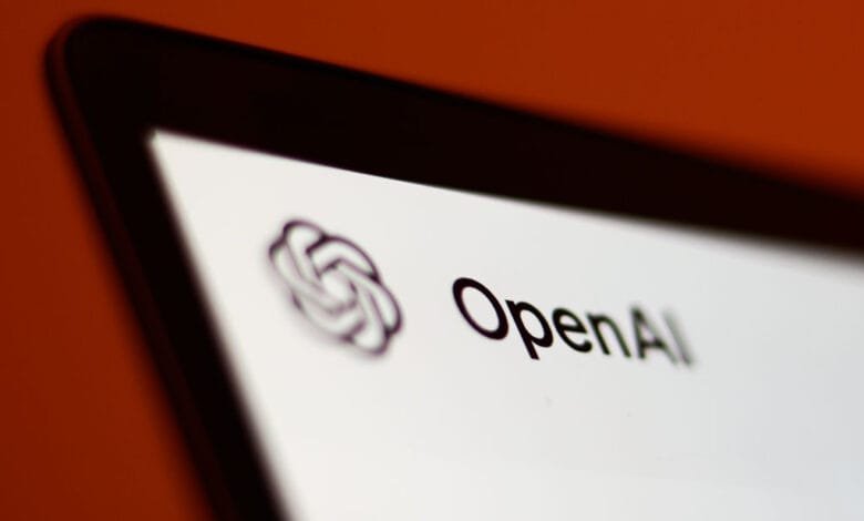 Close-up of a laptop screen showing the OpenAI logo and text on a white background against a blurred orange backdrop.