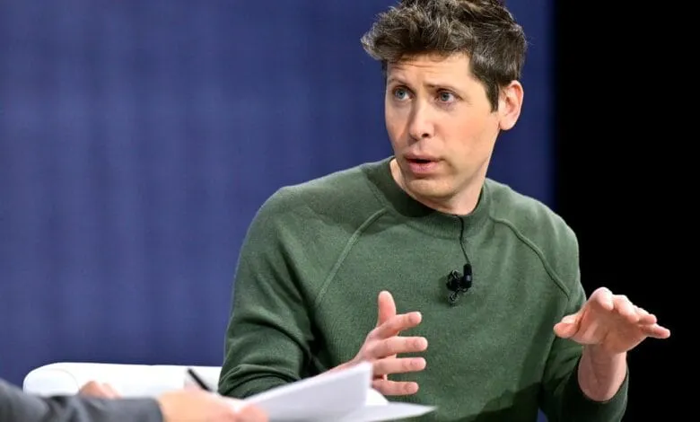 A man with brown hair in a green sweater passionately speaks, gesturing with his hands during a discussion.