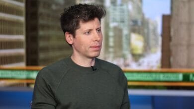 Alex Karp, CEO of Palantir, sits for an interview against a blurred NYC backdrop.