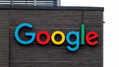 Google's colorful logo on a dark brick building.