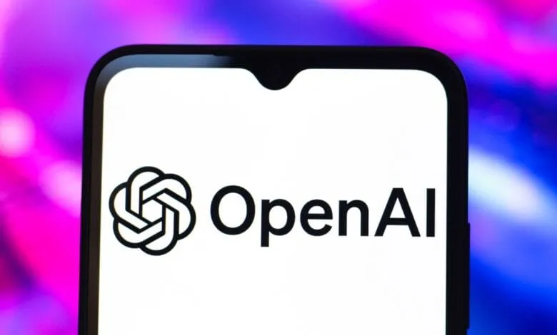 Close-up of a smartphone displaying the OpenAI logo on a white background against a blurred purple and blue backdrop.