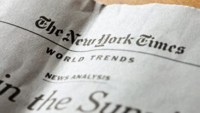 Close-up of a crumpled New York Times newspaper, showing the headline 'World Trends' and part of a story.