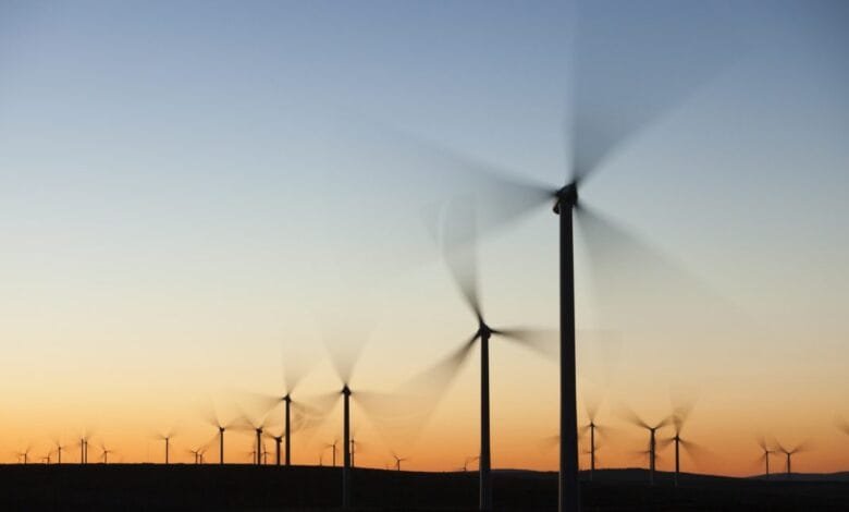 Silhouetted wind turbines spin against a vibrant sunset, showcasing clean energy production.