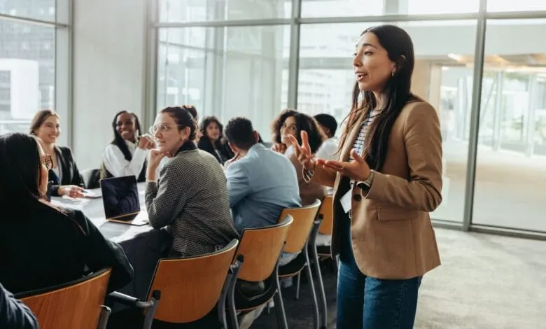 A young woman leads a business meeting, passionately presenting to a diverse group of attentive colleagues.