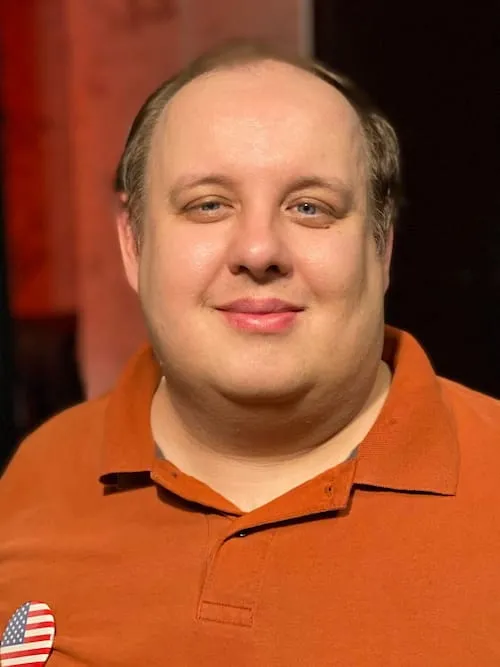 Headshot of Steven Pruitt, wearing an orange polo shirt and an American flag pin.
